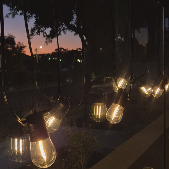 Solar festoon lights glowing at night creating warm ambient backyard garden lighting